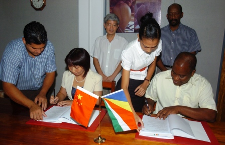 Ambassador Wang and Minister Meriton look on as Mrs Guan and Mr Rose sign the agreement