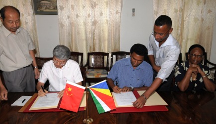 Mr Weng (left) and Mr Faure sign the handing over certificate for the school in the presence of Mrs Simeon