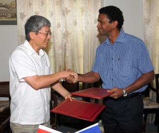 Mr Weng (left) and Mr Faure exchange documents after signing the agreement